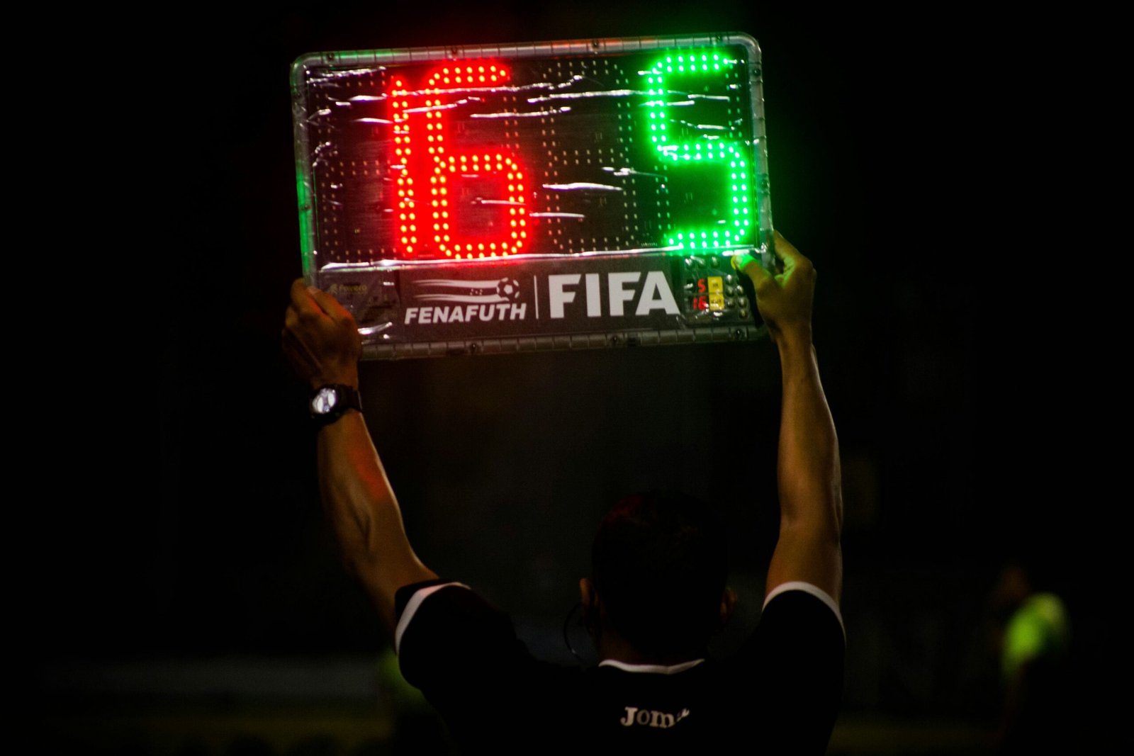 Referee holding up an electronic substitution board during a match